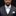 Man wearing a gray suit with a purple bow tie and pocket square against a black background