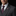 Man wearing a gray suit with a purple tie and floral lapel pin against a black background