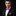 Man wearing a black suit with a pink polka dot bow tie and pocket square on a black background