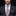 Man wearing a dark suit with a floral tie and matching pocket square on a black background