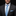 Man wearing a black suit with a blue tie and pocket square on a black background