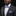 Man wearing a gray suit with a white shirt, purple bow tie, and pocket square on a black background