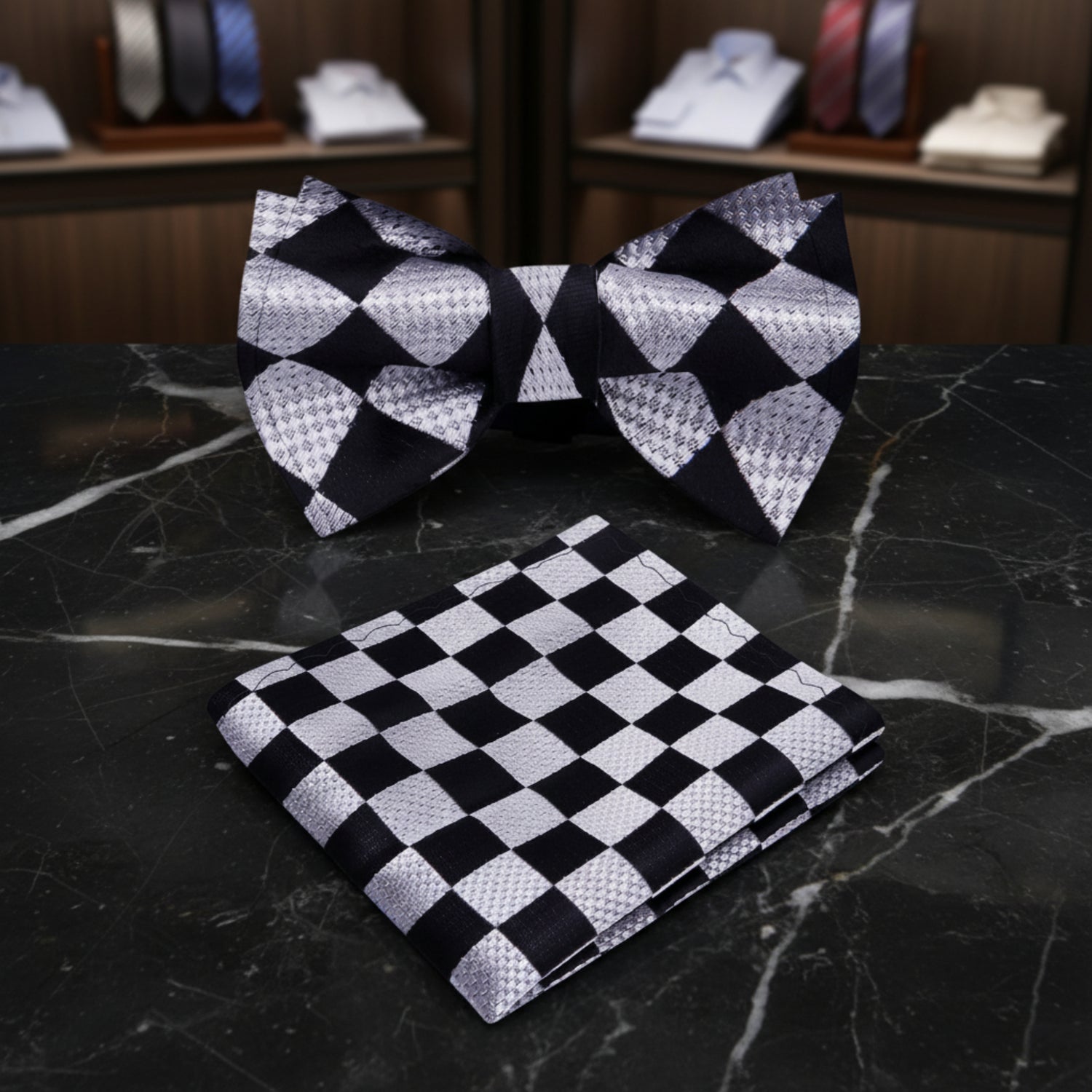 A men's formal accessory set featuring a pre-tied bow tie and a matching folded pocket square, both in a black and silver-gray harlequin checkered pattern 