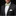 Man wearing a black suit with a white shirt and green patterned bow tie on a black background