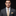 Man wearing a gray suit with a colorful tie and pocket square on a black background