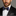 Man wearing a black suit with a colorful bow tie and pocket square on a gray background