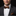 Man wearing a gray suit with a patterned bow tie and pocket square on a black background