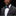 Man wearing a gray suit with a colorful bow tie and pocket square on a black background