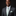 Man wearing a gray suit with a green tie and pocket square on a black background