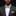 Man wearing a black suit with a white shirt and gold bow tie against a dark background