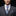 Man wearing a gray suit with a blue tie and pocket square against a black background
