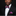 Man wearing a black suit with a colorful bow tie and pocket square on a black background