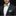 Man wearing a black suit with a green and blue bow tie and pocket square on a black background