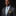 Man wearing a gray suit with a blue tie featuring yellow chevrons and an orange pocket square on a black background.