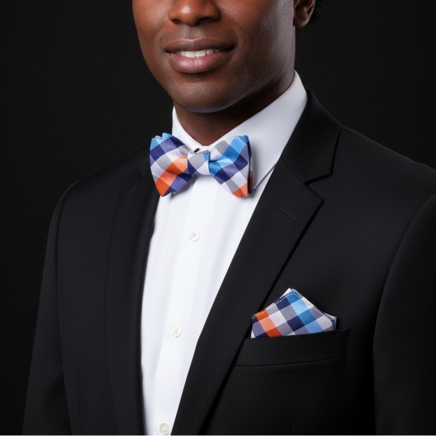 Man wearing a black suit with a colorful bow tie and pocket square on a black background