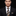 Man wearing a black suit with a patterned tie and pocket square on a black background