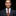 Man wearing a dark suit with a colorful tie against a black background