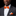 Man wearing a gray suit with an orange bow tie and pocket square on a black background