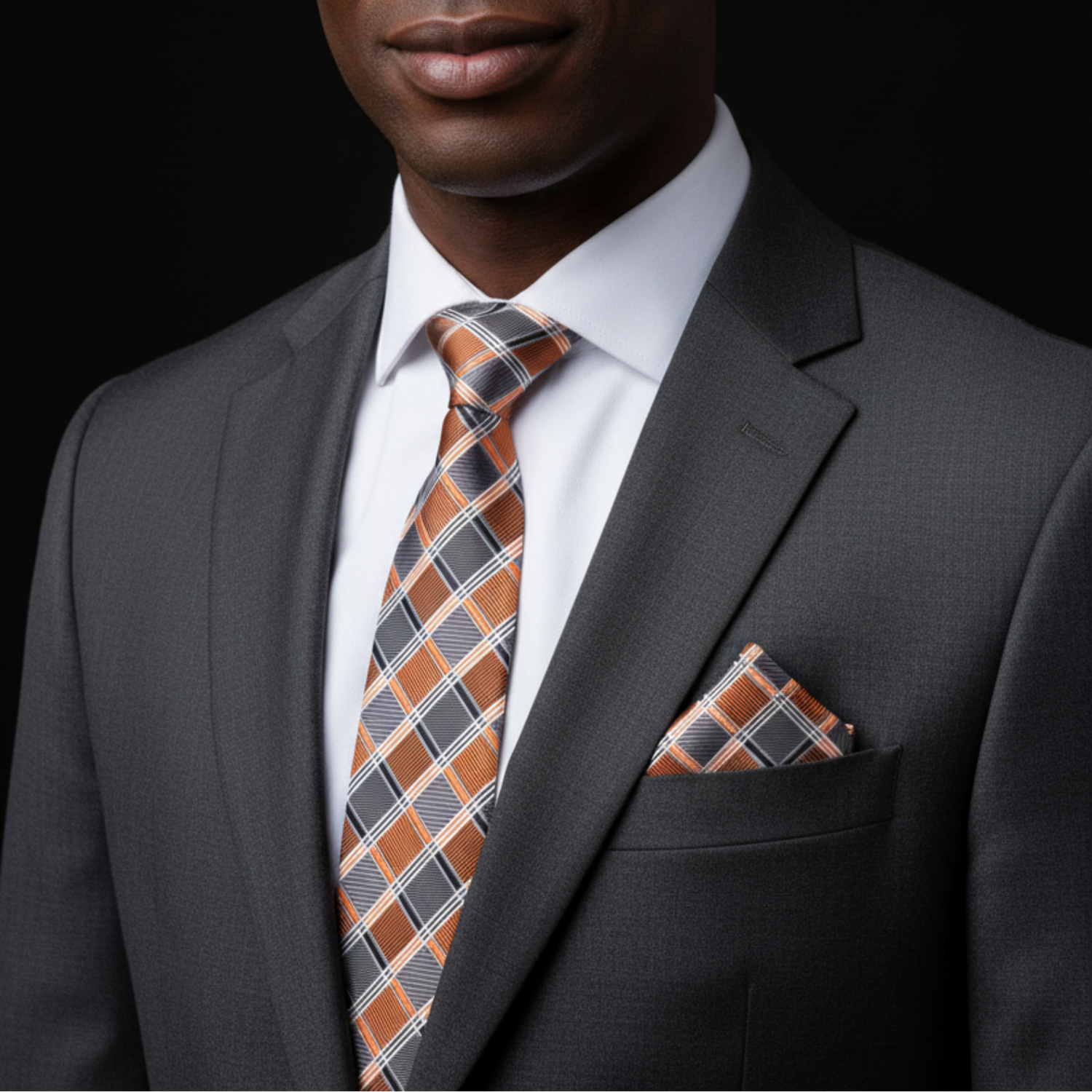 Man wearing a gray suit with a patterned tie and pocket square on a black background