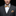 Man wearing a gray suit with an orange and blue patterned bow tie and pocket square on a black background