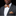 Man wearing a gray suit with a patterned bow tie and pocket square on a black background