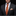 Man wearing a black suit with an orange striped tie and floral pocket square on a dark background