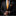 Man wearing a black suit with an orange tie and pocket square on a black background