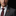 Man wearing a gray suit with a maroon tie and floral lapel pin on a black background
