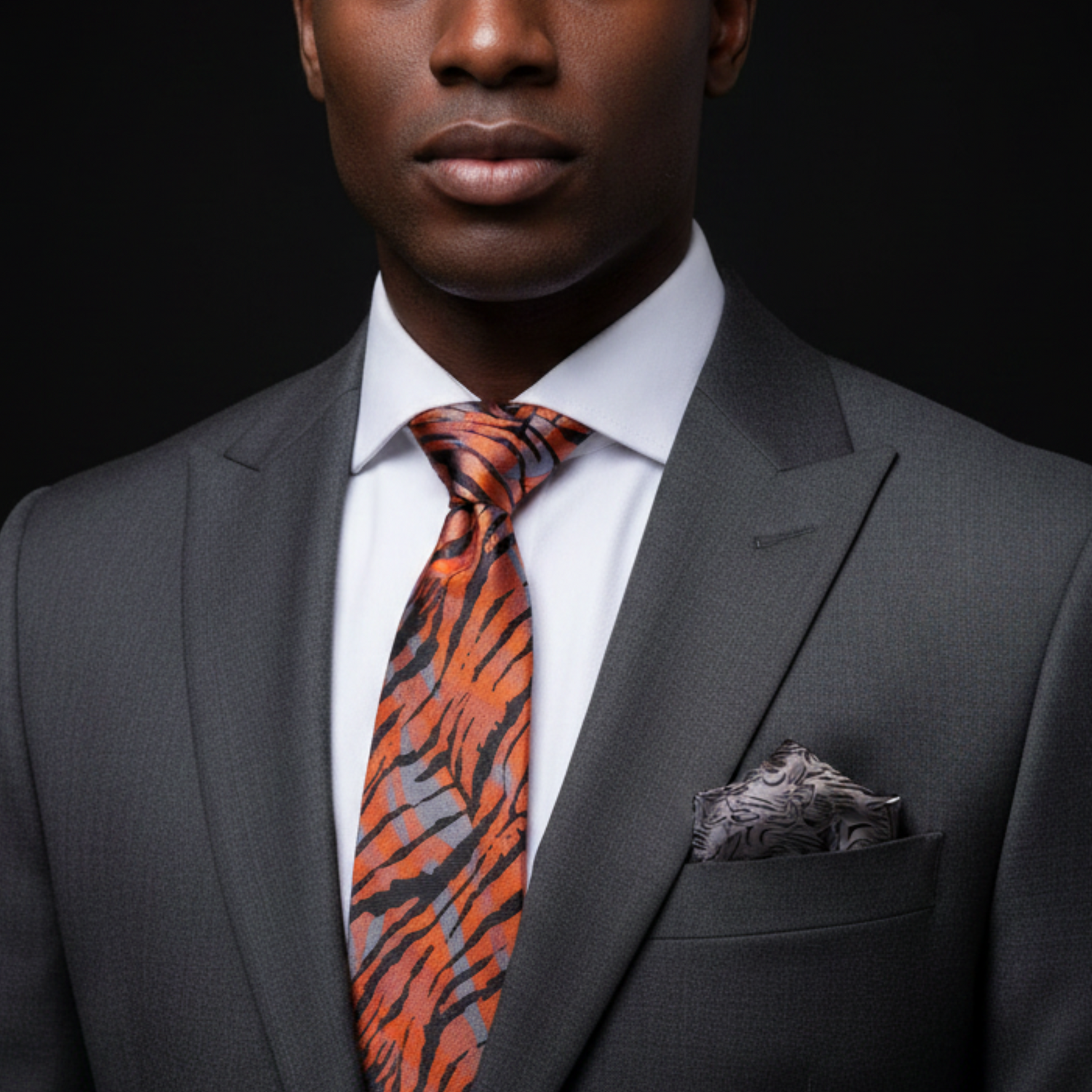Man wearing a gray suit with a tiger-striped tie against a black background
