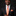 Man wearing a black suit with an orange tie and pocket square on a dark background