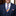 Man wearing a navy suit with an orange and blue striped tie and matching pocket square.