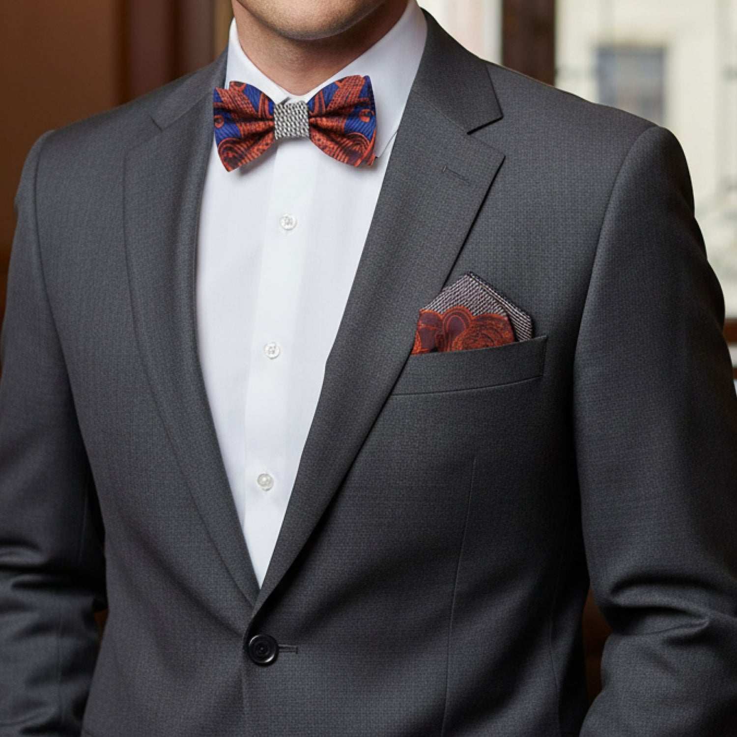 Man wearing a gray suit with a patterned bow tie and pocket square.