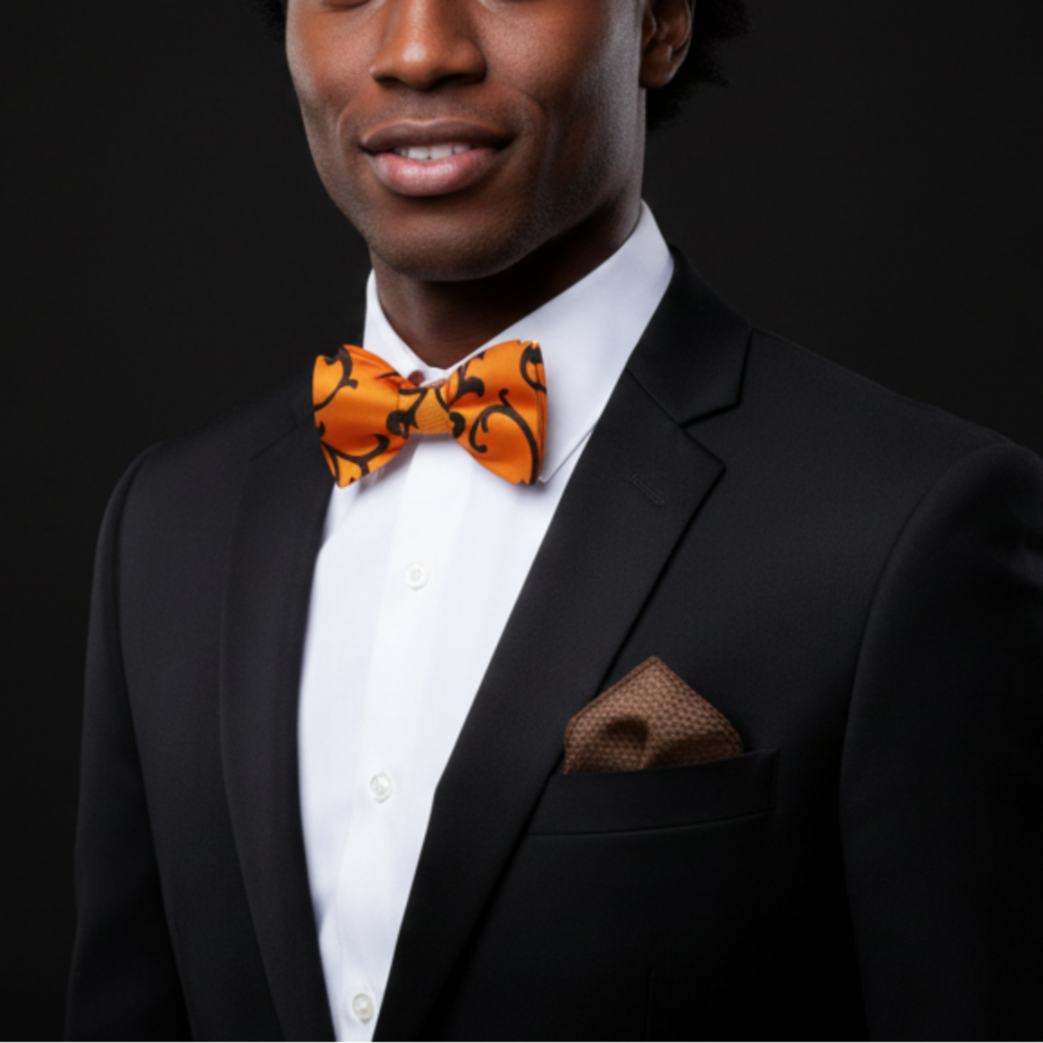 Man wearing a black suit with an orange bow tie on a black background