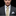 Man wearing a gray suit with a white shirt and gold tie against a black background