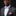 Man wearing a gray suit with a colorful bow tie and pink pocket square on a black background