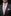 Man wearing a black suit with a pink tie and matching pocket square against a dark background