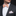 Man wearing a gray suit with an orange paisley bow tie and pocket square against a black background