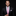 Man wearing a black suit with a pink striped tie against a dark background