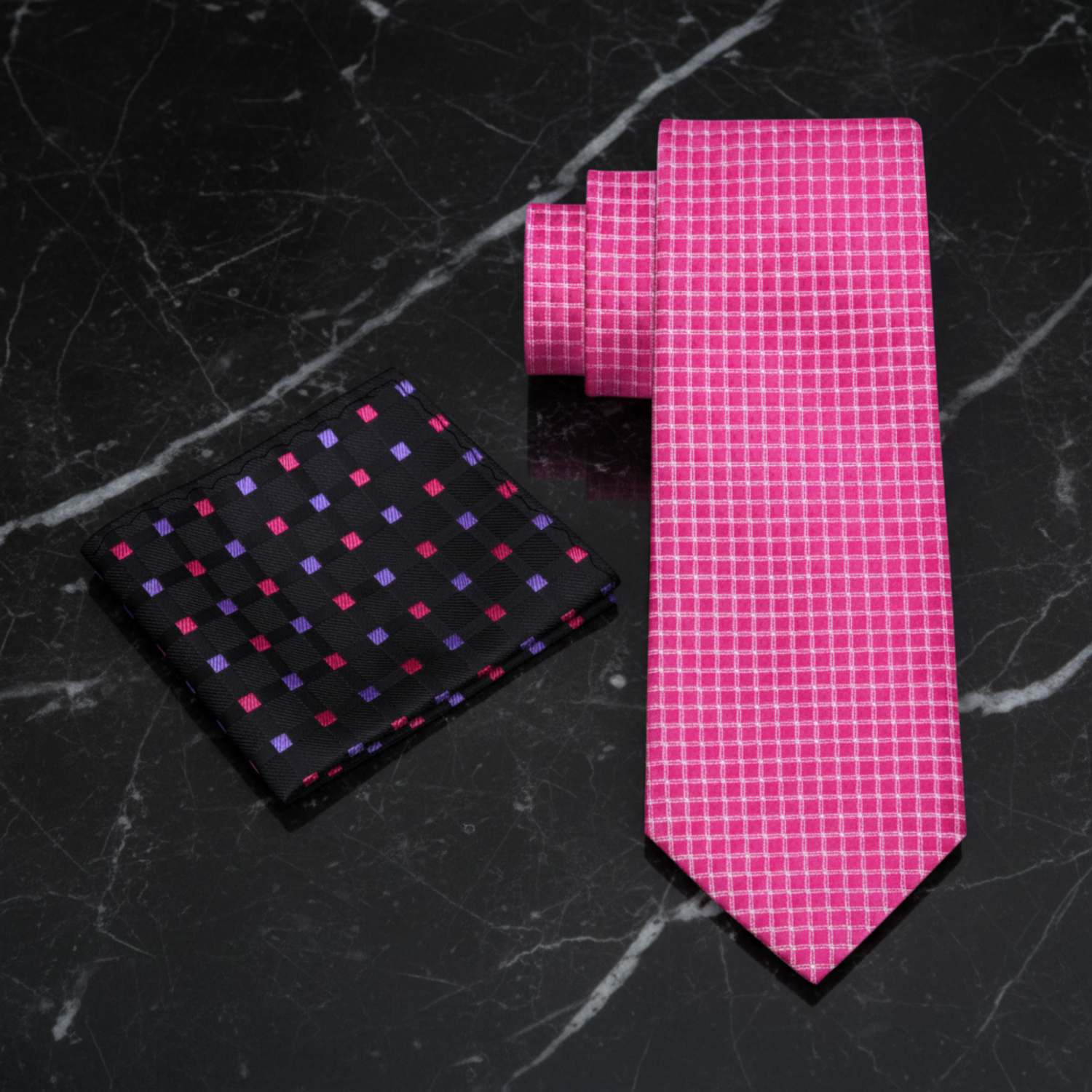 A men's necktie and matching pocket square set on a white background. The necktie is bright pink with a fine white grid pattern, and the matching pocket square is black with small pink, purple, and red square dots.