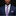 Man wearing a navy suit with a purple paisley tie and pocket square on a black background