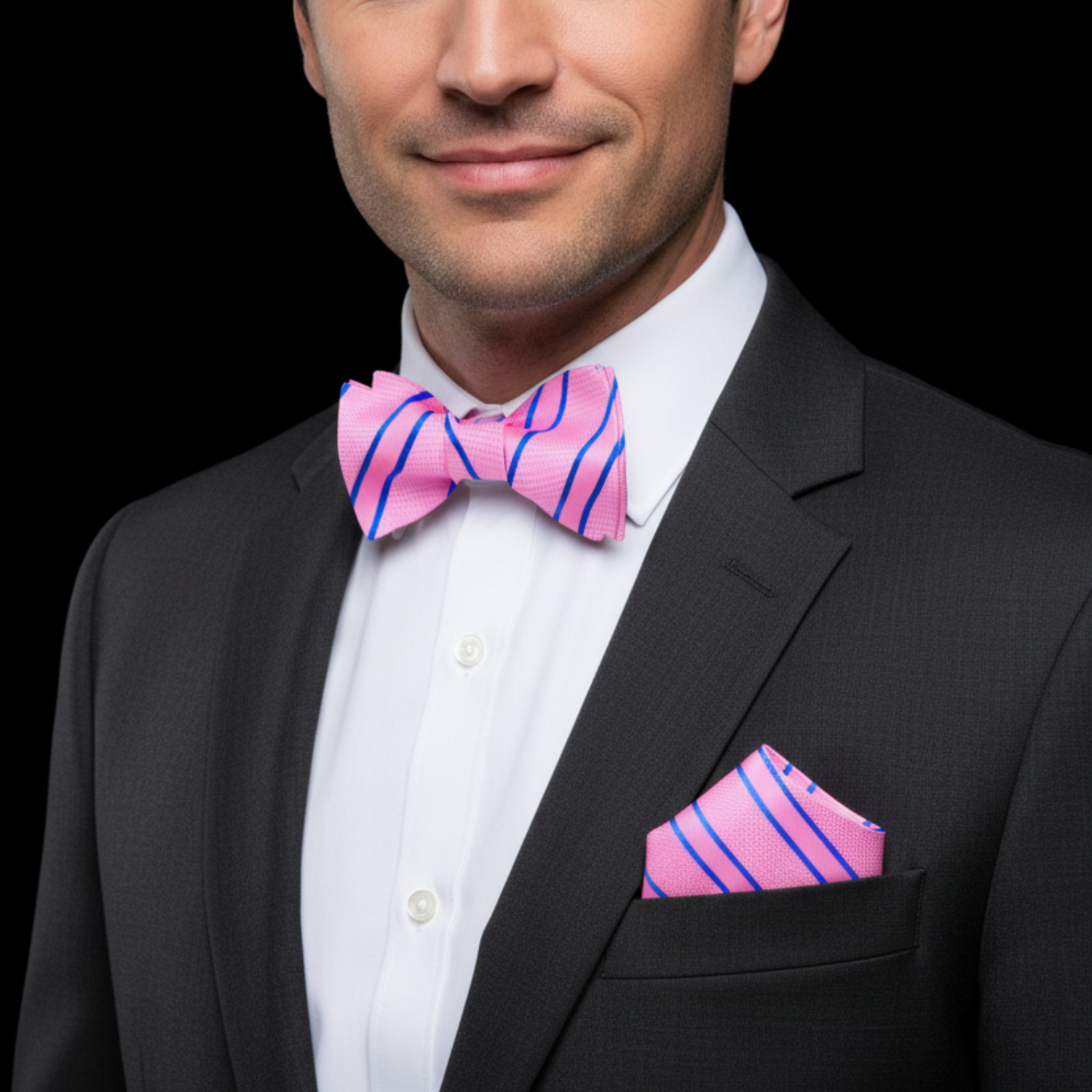 Man wearing a black suit with a pink striped bow tie and pocket square on a black background