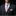 Man wearing a dark suit with a pink patterned tie and pocket square on a black background