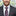 Man wearing a gray suit with a colorful tie and pocket square, blurred cityscape background