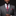 Man wearing a gray suit with a red paisley tie and pocket square against a black background