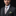 Man wearing a formal black suit with a patterned tie and pocket square on a dark background