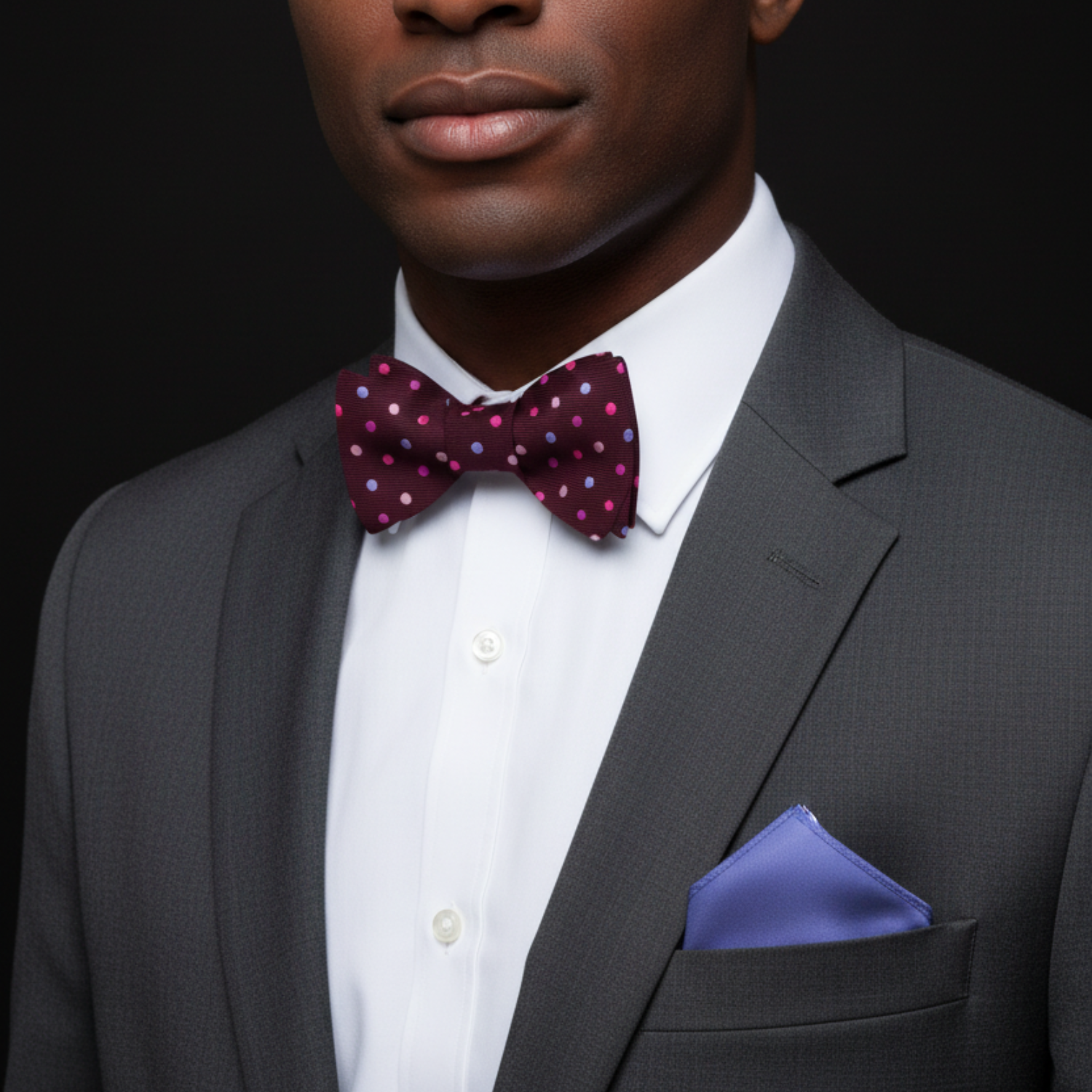 Man wearing plum with multi color dots bow tie and accenting light purple square