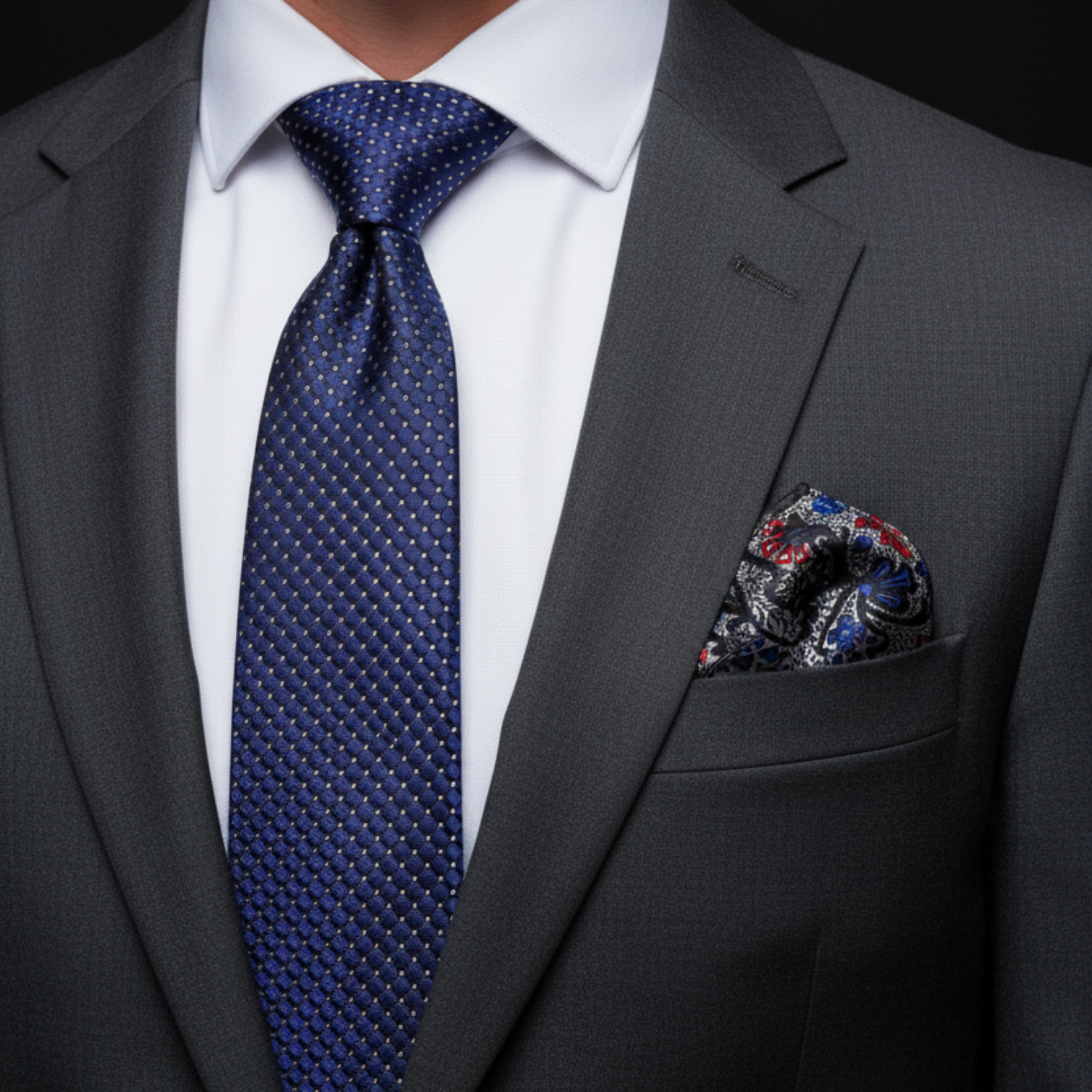 Gray suit with blue tie and patterned pocket square on a black background