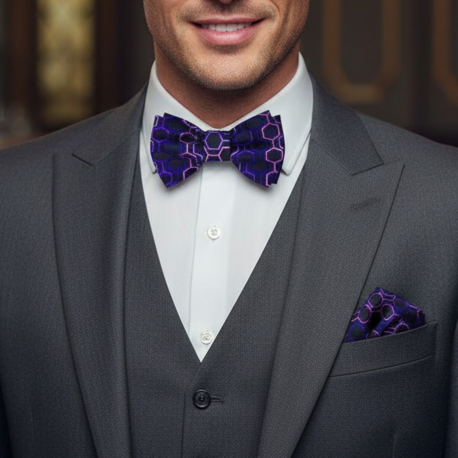 Man wearing a gray suit with a purple patterned bow tie and pocket square.