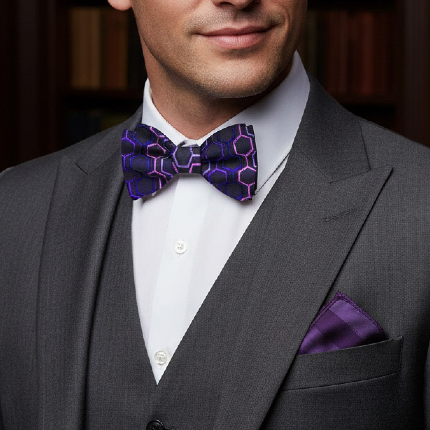 Man wearing a gray suit with a purple bow tie and pocket square.