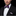 Man wearing a black suit with a purple bow tie and matching pocket square on a black background